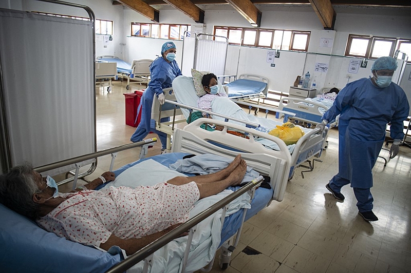 Health professionals assist COVID-19 patient Aquilia Huamani (top), 63, in the Intensive Care Unit of the Alberto Sabogal Sologuren Hospital, in Lima, on January 12, 2022. – Peru registered a record 24,288 new cases of COVID-19 in the last 24 hours, as a third wave of the pandemic hits the country driven by the Omicron variant. (Photo by Ernesto BENAVIDES / AFP)